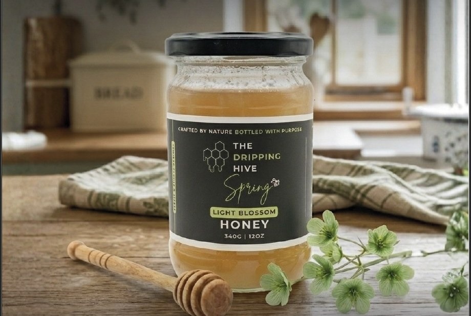 Spring honey jar in a kitchen with a wooden dipper and green hellebore blossoms